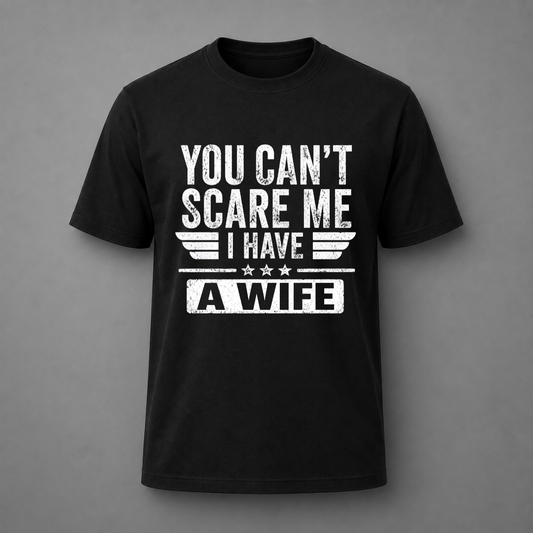 A black short-sleeve crewneck t-shirt with a distressed white graphic print on the front that reads 'YOU CAN'T SCARE ME I HAVE A WIFE' with wing and star details, displayed against a solid gray background.