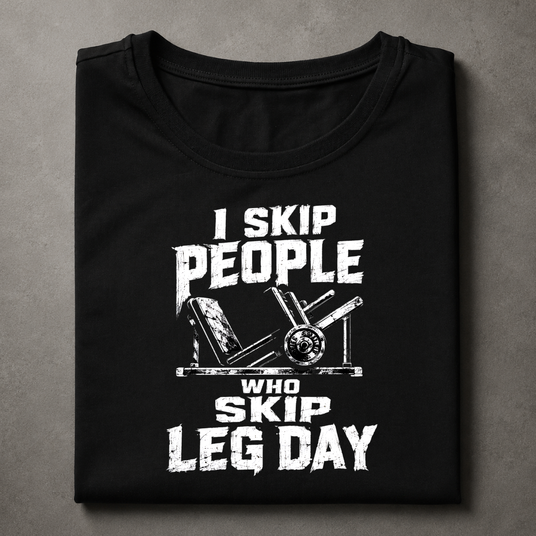 A folded black t-shirt with a distressed white graphic print that reads 'I SKIP PEOPLE WHO SKIP LEG DAY' alongside an illustration of a leg extension machine, displayed on a textured gray background.