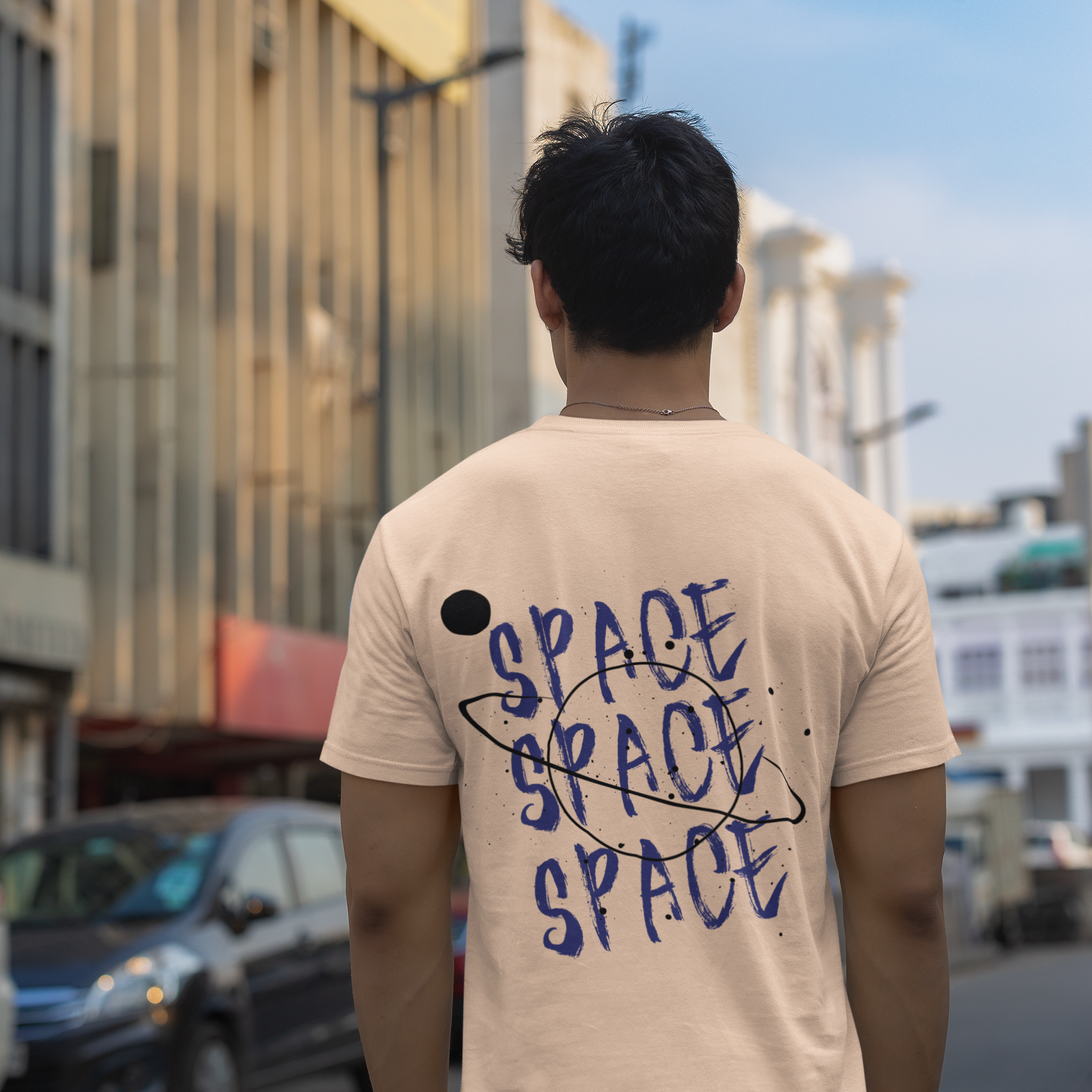 Person wearing a beige t-shirt with 'SPACE SPACE SPACE' text in an urban setting