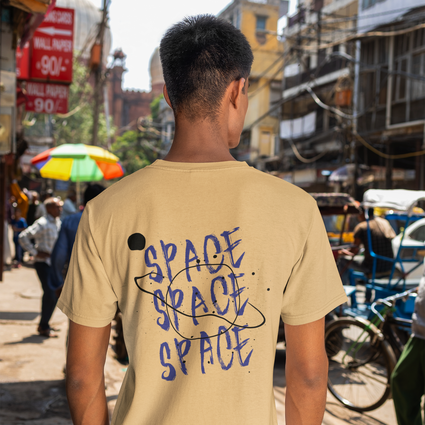 Person wearing a beige t-shirt with 'SPACE' text in an urban setting