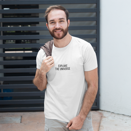 Man wearing a t-shirt with 'Explore the Universe' text, standing against a wall.