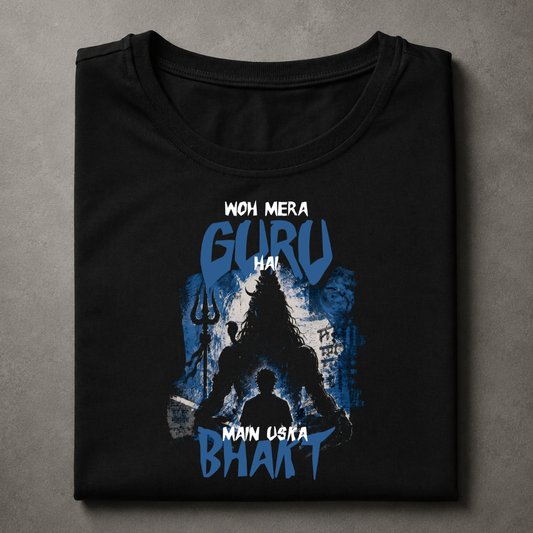 A folded black t-shirt with a blue and white graphic print featuring a silhouette of a guru and the text 'WOH MERA GURU HAI MAIN USKA BHAKT', displayed on a textured gray background.
